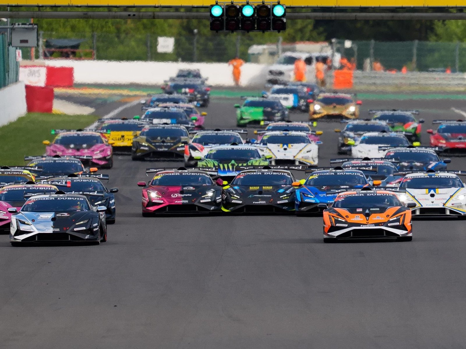 Multiple Lamborghini Huracán Super Trofeo EVO2 race cars lined up on the starting grid under green lights