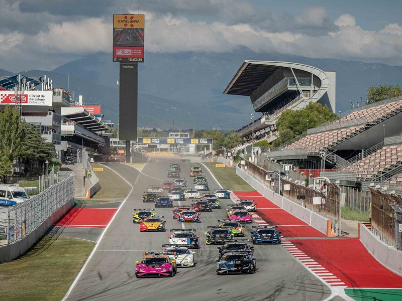 A packed grid of Lamborghini Huracán Super Trofeo EVO2 race cars competing at Barcelona with grandstands and mountains in the background
