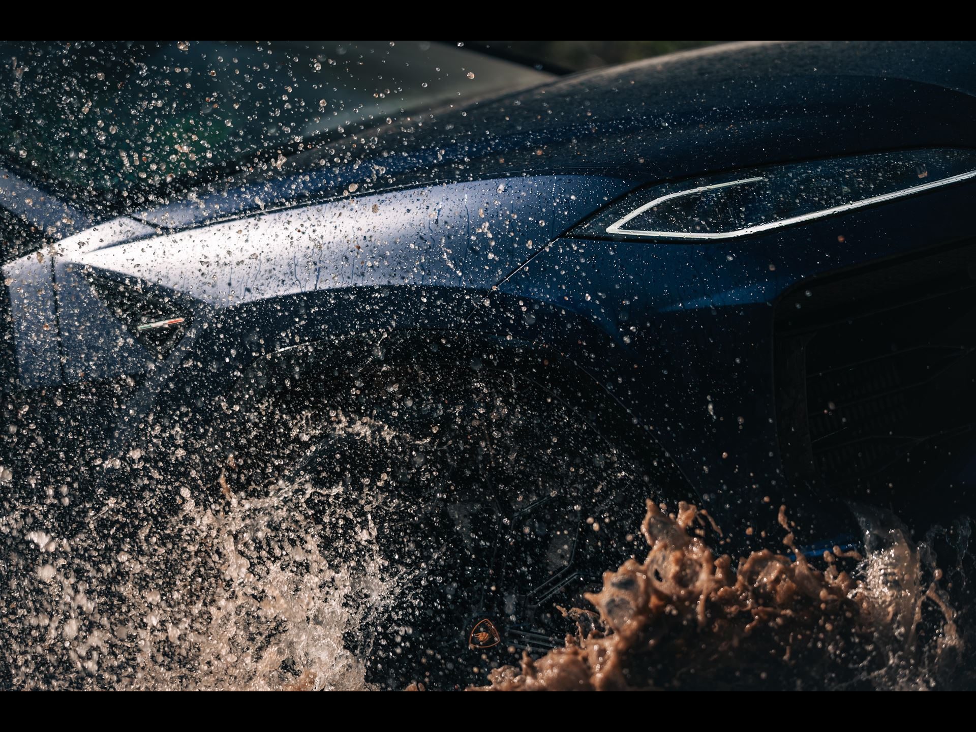 The Urus Se Staked Lamborghini'S Hybrid Credibility On Sardinian Dirt 5 Close-up of blue lamborghini urus front end splashing through muddy water, headlights and badge visible
