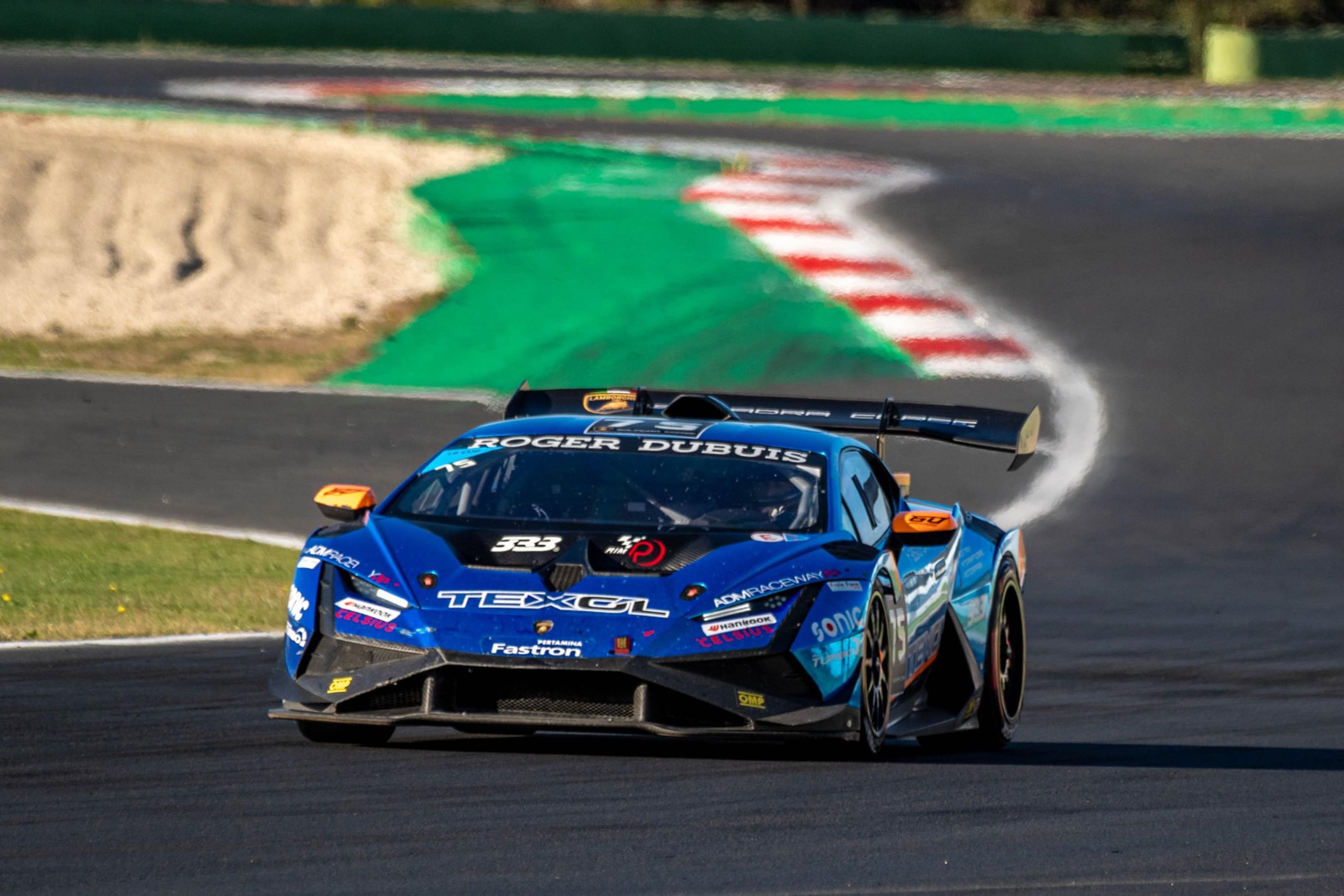 Blue lamborghini huracán super trofeo evo2 approaching a corner at vallelunga showing racing livery and sponsor logos