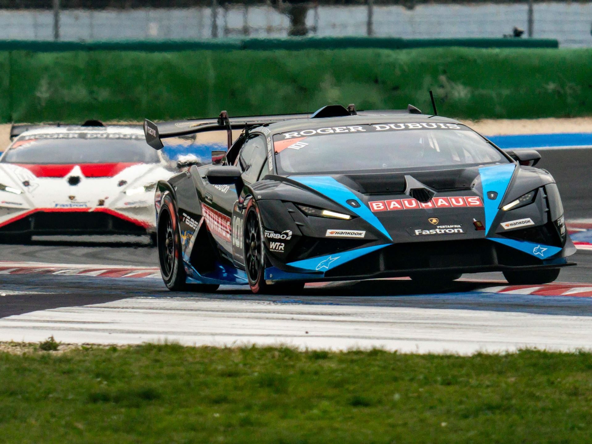 A black and blue lamborghini huracán super trofeo evo2 race car at speed on the misano circuit