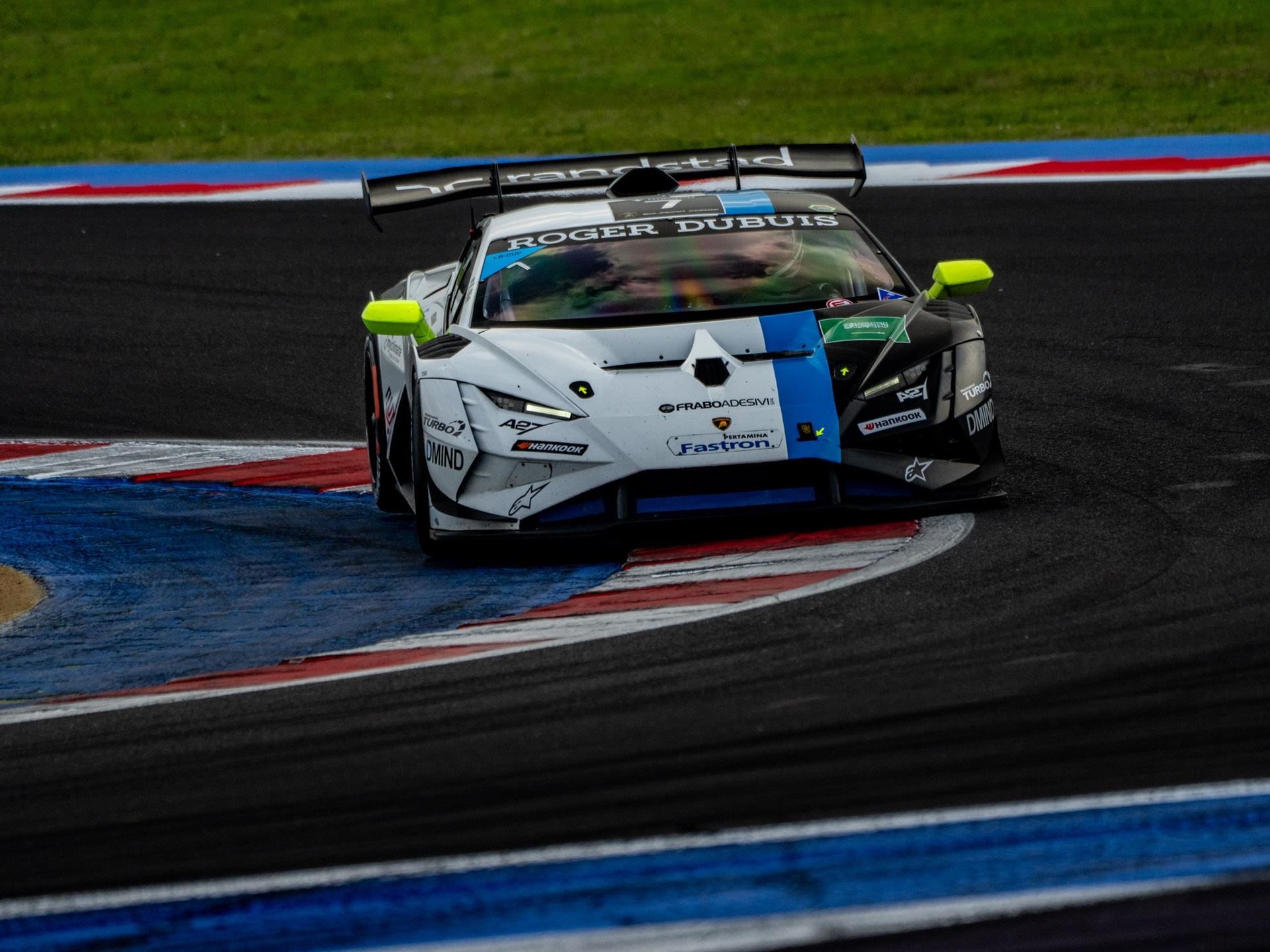 A white, black, and blue lamborghini huracán super trofeo evo2 taking a sharp corner at misano
