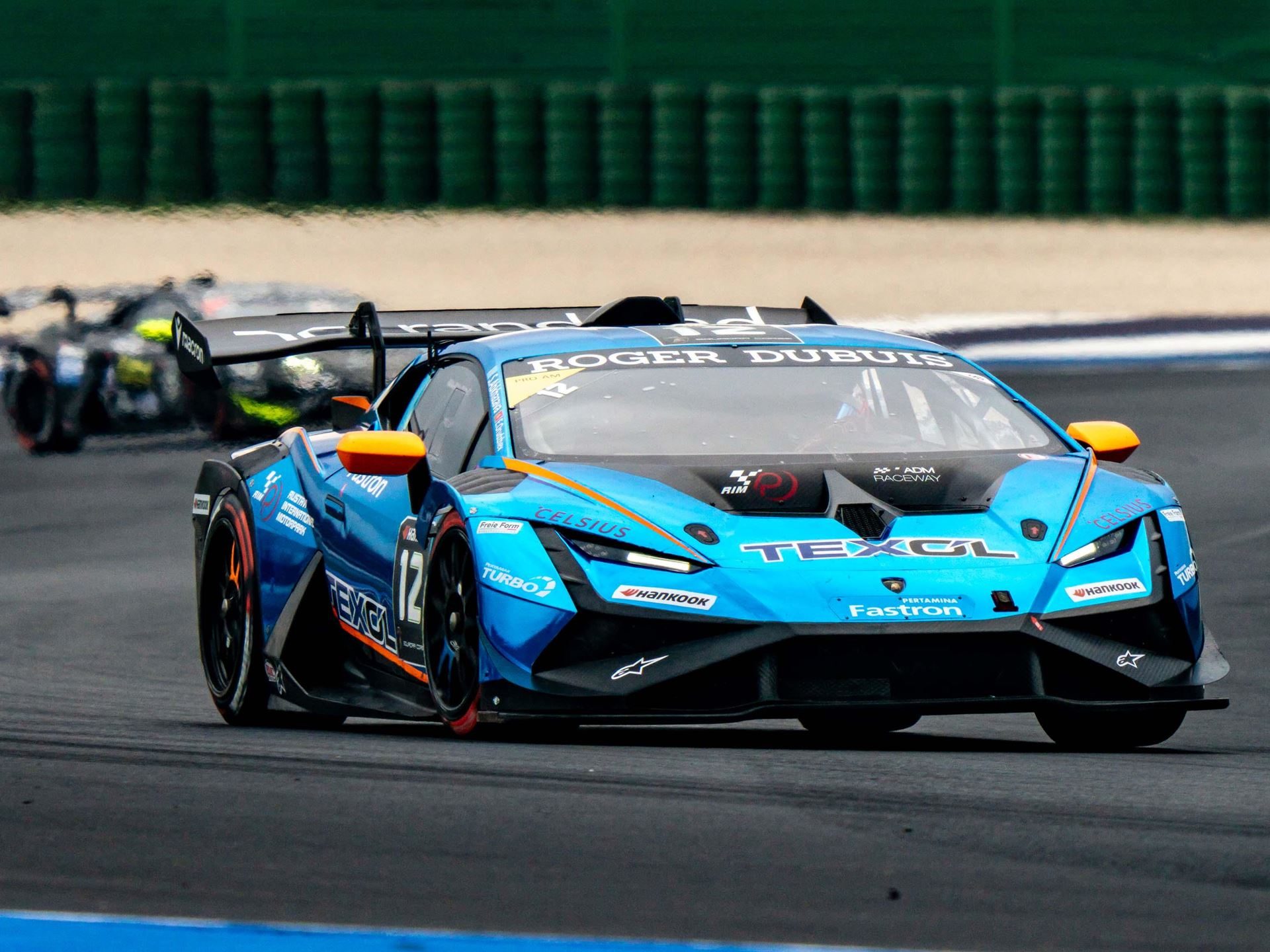 A blue and orange lamborghini huracán super trofeo evo2 at speed on the misano circuit