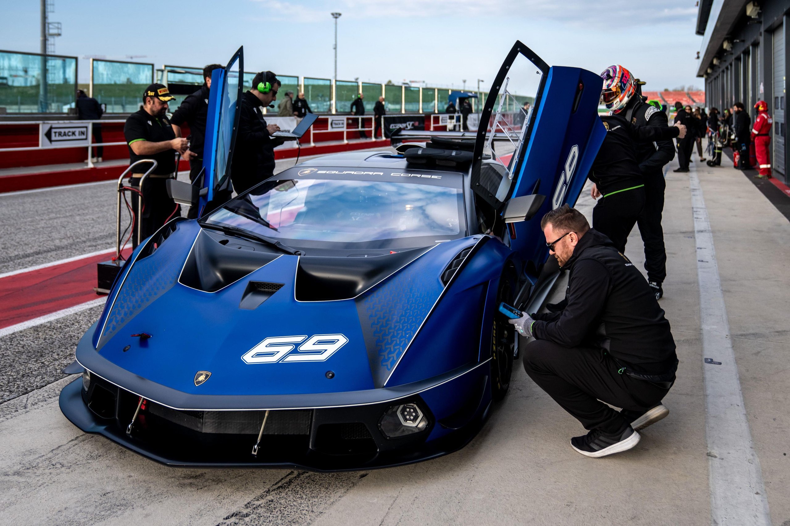 Four Weekends, 40 Cars, Factory Drivers: Inside Lamborghini'S 2026 Essenza Scv12 Program 9 Blue lamborghini essenza scv12 with scissor doors open surrounded by pit crew in a professional pit lane setting