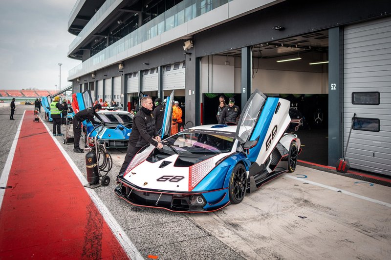 Lamborghini Essenza SCV12 in white and blue livery being prepared by pit crew in the pit lane with another SCV12 visible in the background
