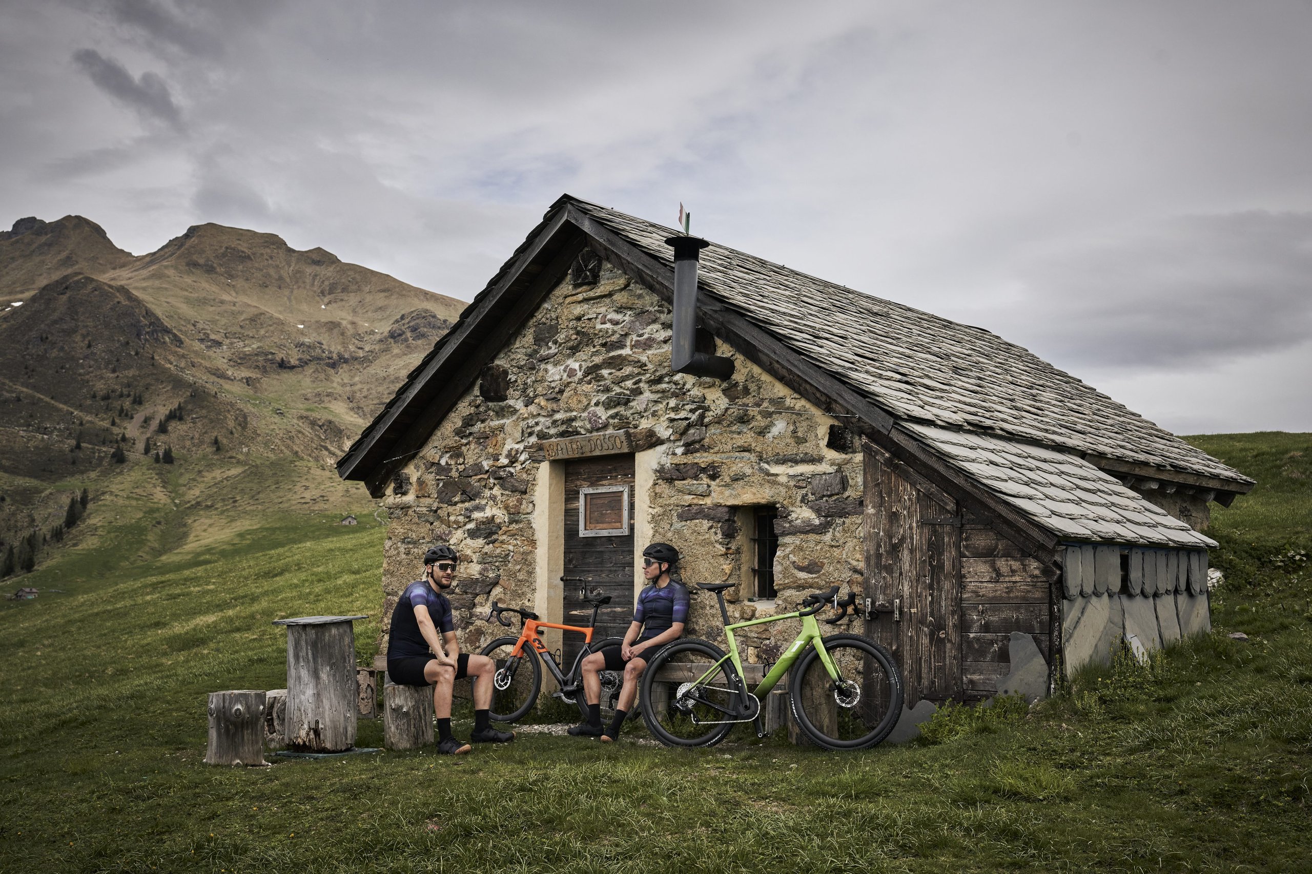 Lamborghini'S Centro Stile Designed Two New 3T Bicycles, And They Cost Less Than A Set Of Revuelto Brake Pads 9 Two cyclists resting with their 3t x automobili lamborghini bicycles in front of a rustic stone hut in an alpine mountain landscape