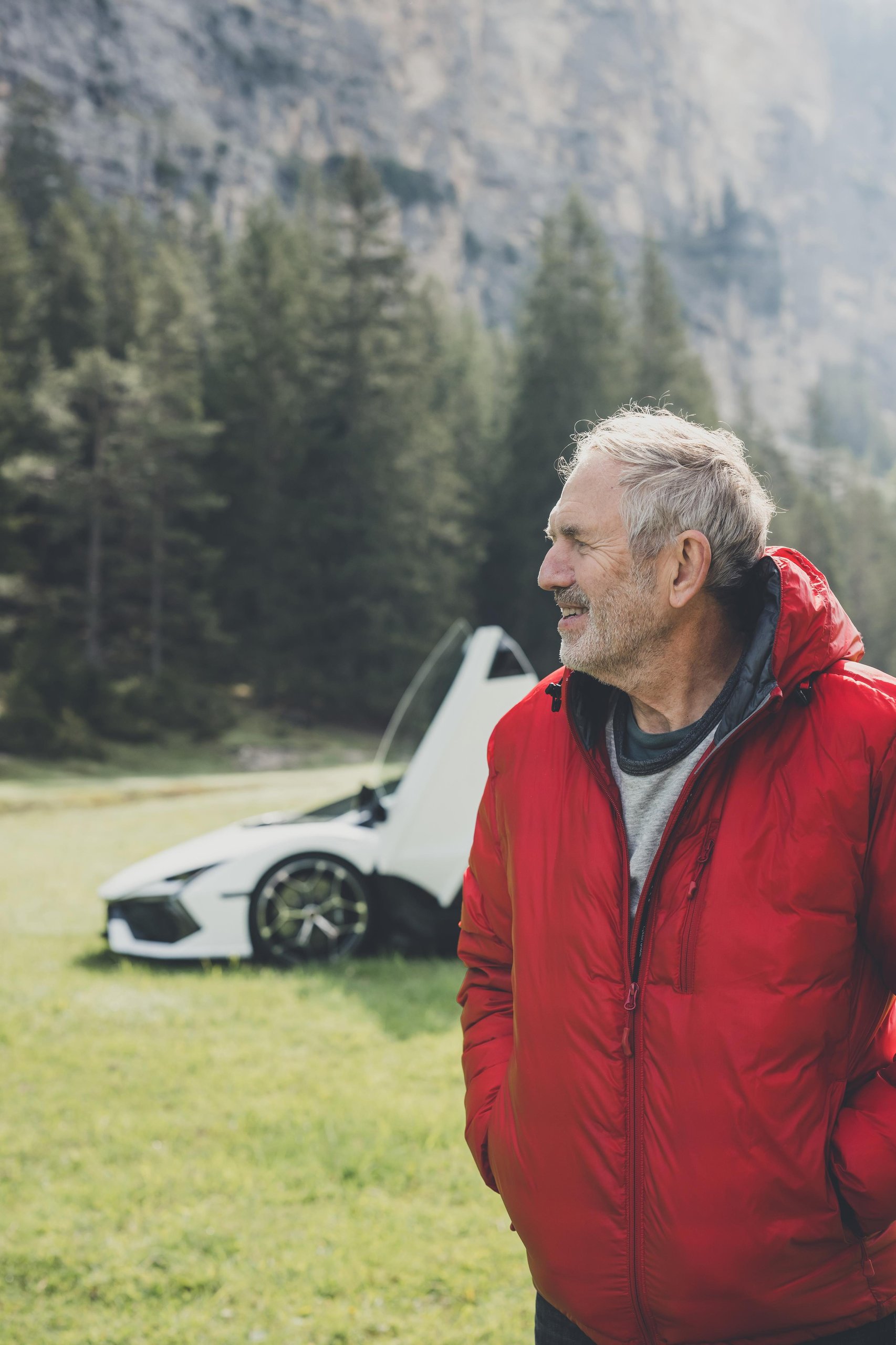 Anton Corbijn Photographs The Revuelto Like A Rock Star, And That'S Exactly Lamborghini'S Point 13 Anton corbijn standing in a grassy field with a white lamborghini revuelto and its scissor door open in the background