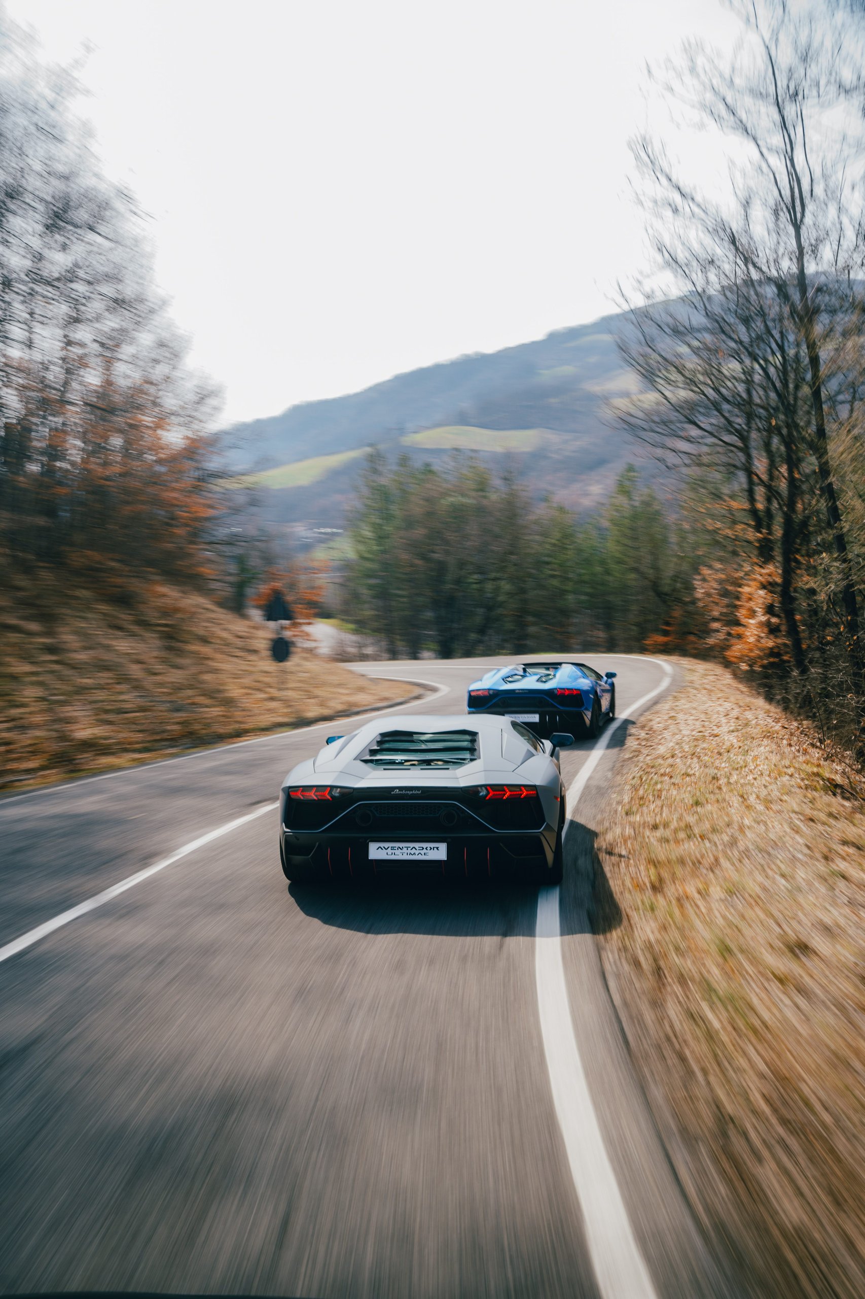 Aventador Ultimae'S Italian Farewell Drive Stages The End Of Lamborghini'S Pure V12 Era 5 Grey aventador ultimae leading a blue ultimae on a winding mountain road with motion blur
