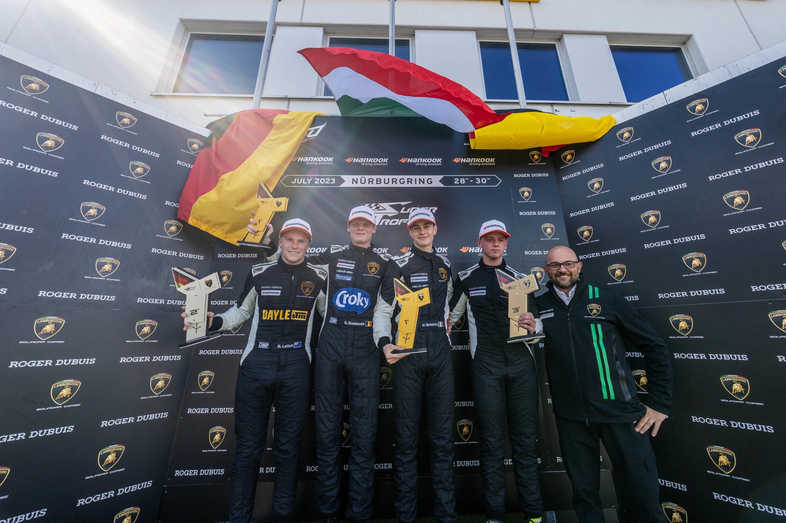 A 17-Year-Old Egyptian Just Rewrote The Record Books At Nürburgring'S Super Trofeo Europe Round 9 Four race drivers and a team member celebrate on the podium holding trophies with lamborghini and roger dubuis branding behind them