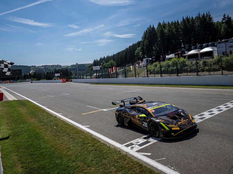 Black and gold Lamborghini Huracán Super Trofeo EVO2 crossing the finish line at Spa-Francorchamps with checkered flag