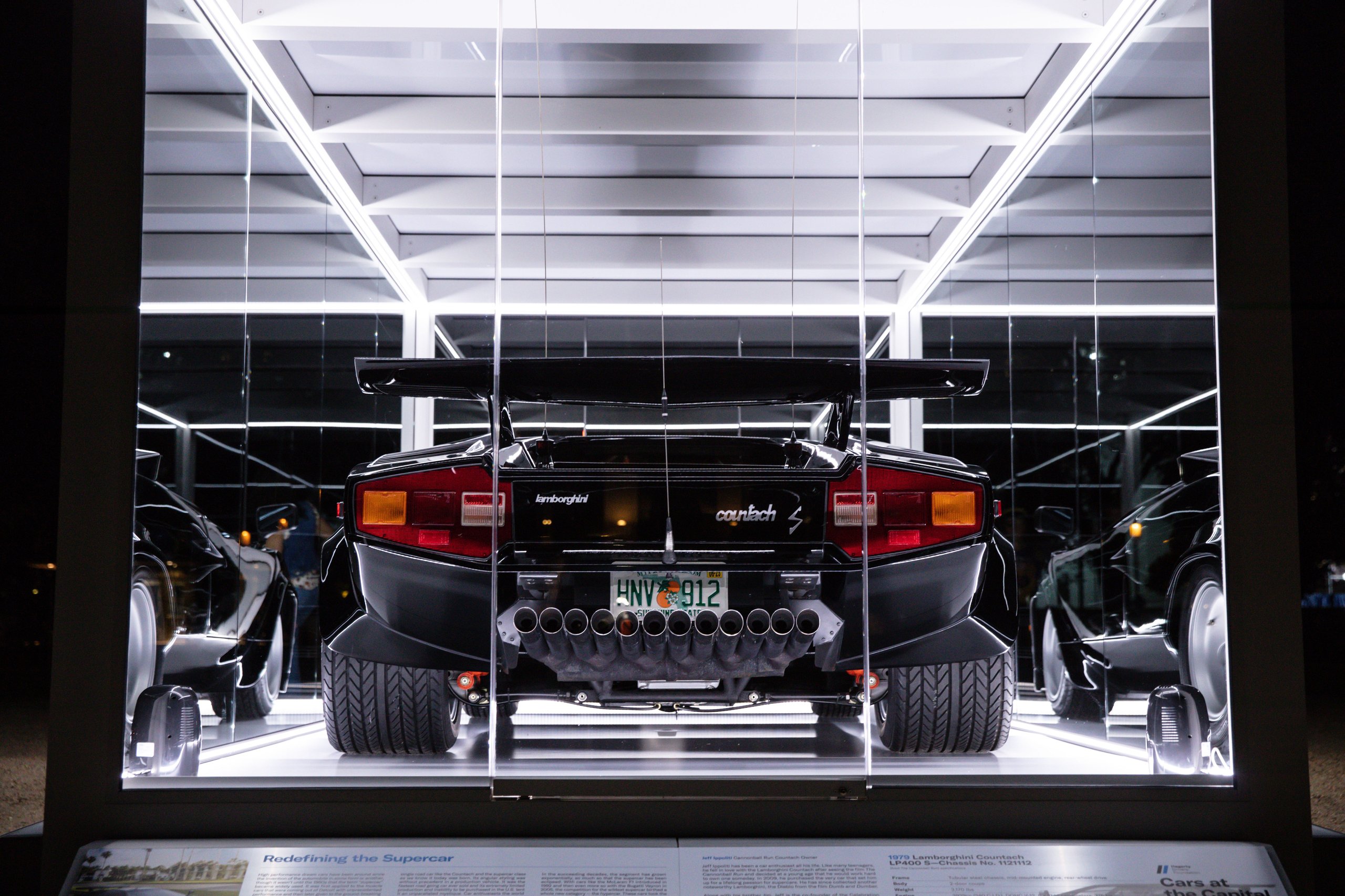 The 'Cannonball Run' Countach Now Sits On The National Mall, Officially One Of America'S Most Important Cars 5 Rear view of the black cannonball run lamborghini countach lp 400 s showing its distinctive taillights, wide tires, and multiple exhaust pipes in an illuminated glass case at night