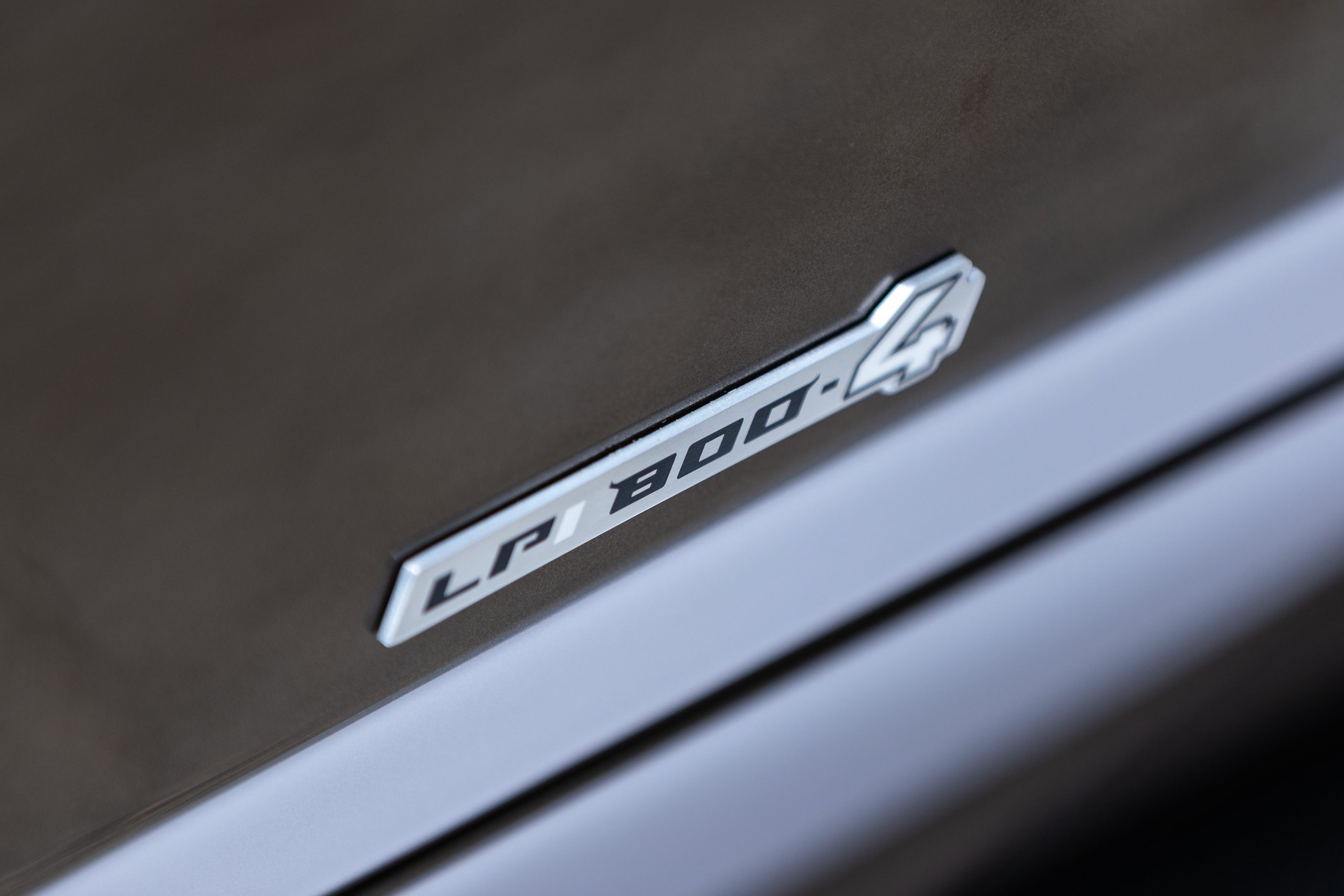 Lamborghini Handed Over Two Countach Lpi 800-4S At Monterey, And The Real Story Is What That Ceremony Signals 5 Close-up of the lp 800-4 badge on the side of the lamborghini countach lpi 800-4 showing metallic finish and embossed lettering