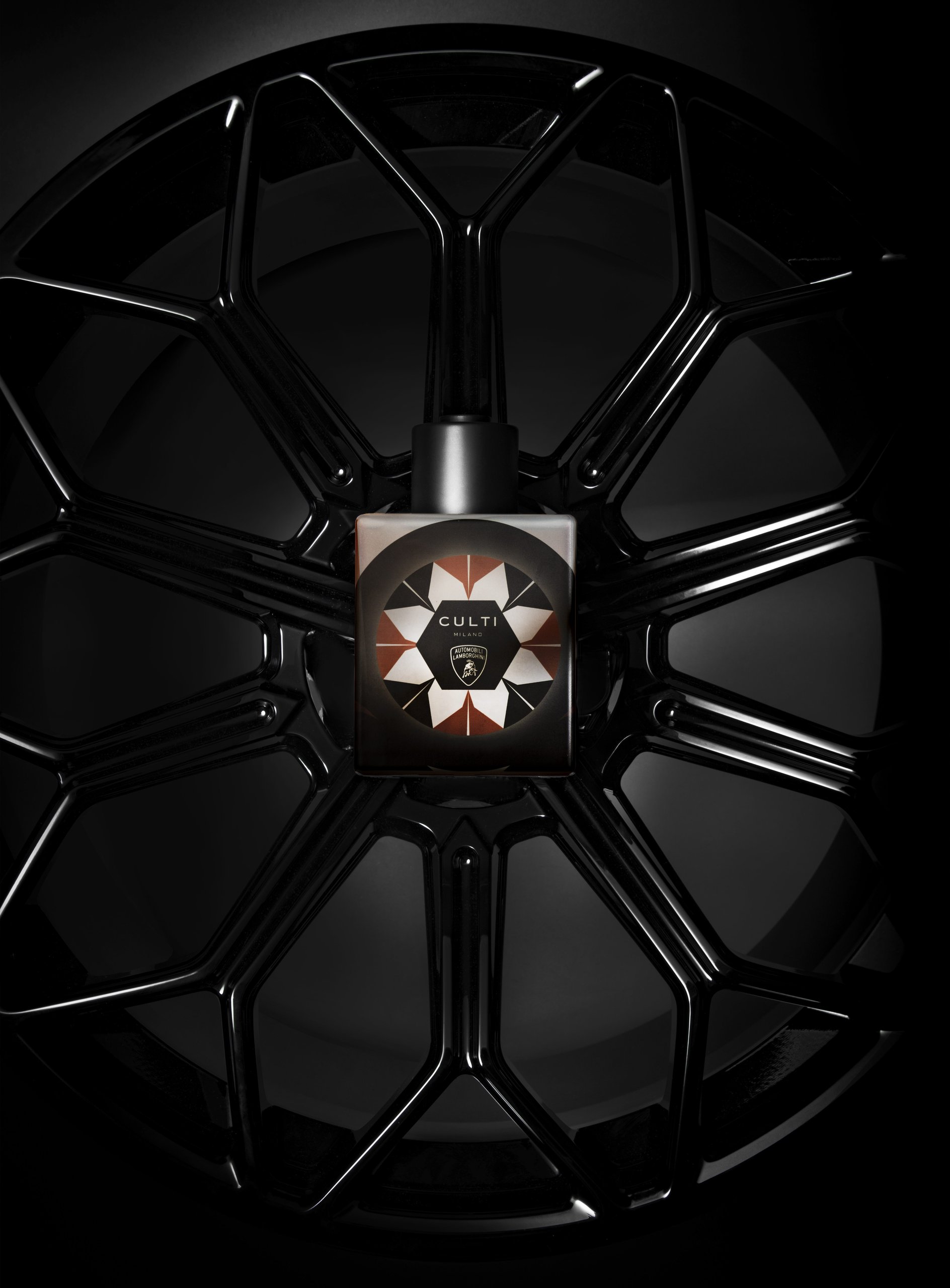Overhead view of the culti milano for automobili lamborghini diffuser bottle placed centrally within a black lamborghini wheel