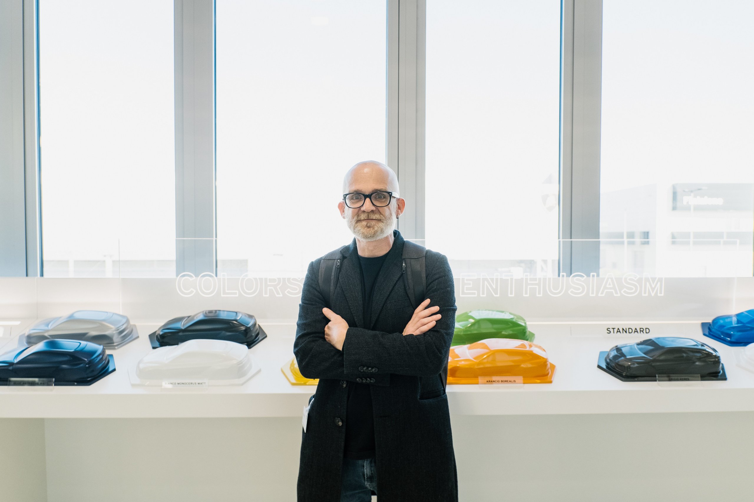 Francesco poroli standing in front of a display of colorful miniature lamborghini models and a 'colors of enthusiasm' sign