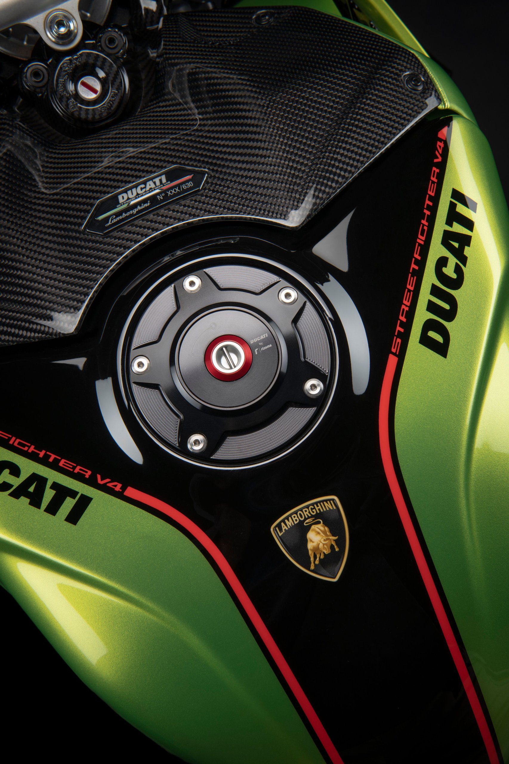 The Ducati Streetfighter V4 Lamborghini Puts The Huracán Sto In Your Garage On Two Wheels 5 Close-up of the ducati streetfighter v4 lamborghini fuel tank showing dual ducati and lamborghini branding with a limited edition numbered plaque and carbon fiber accents