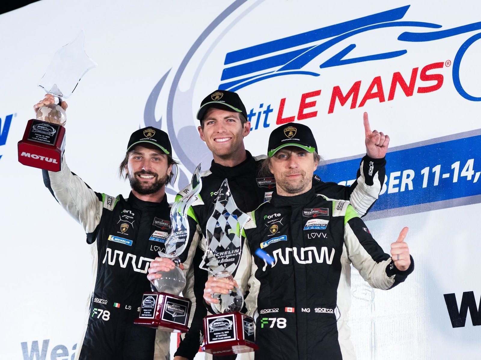 Forte Racing drivers Loris Spinelli, Misha Goikhberg, and Patrick Liddy celebrate on the Petit Le Mans podium with trophies