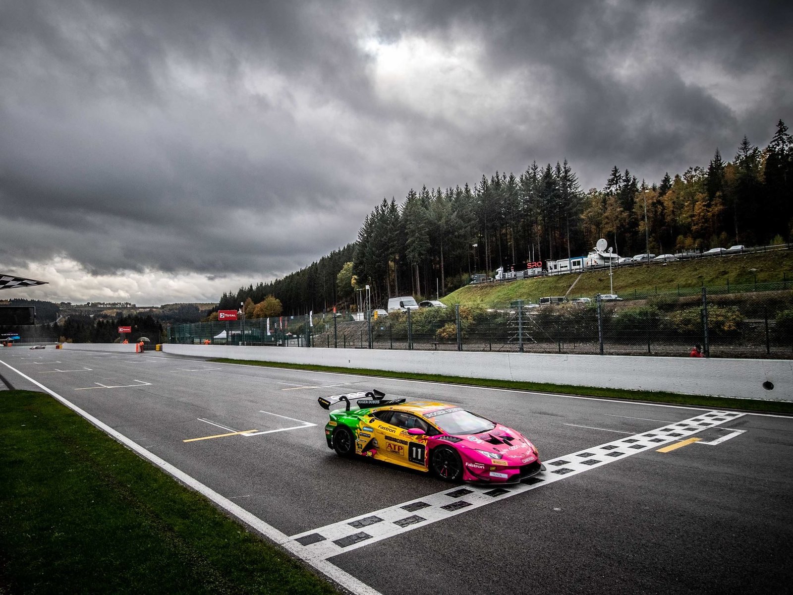 Lamborghini Huracán Super Trofeo race car with colorful livery at Spa-Francorchamps under dramatic skies