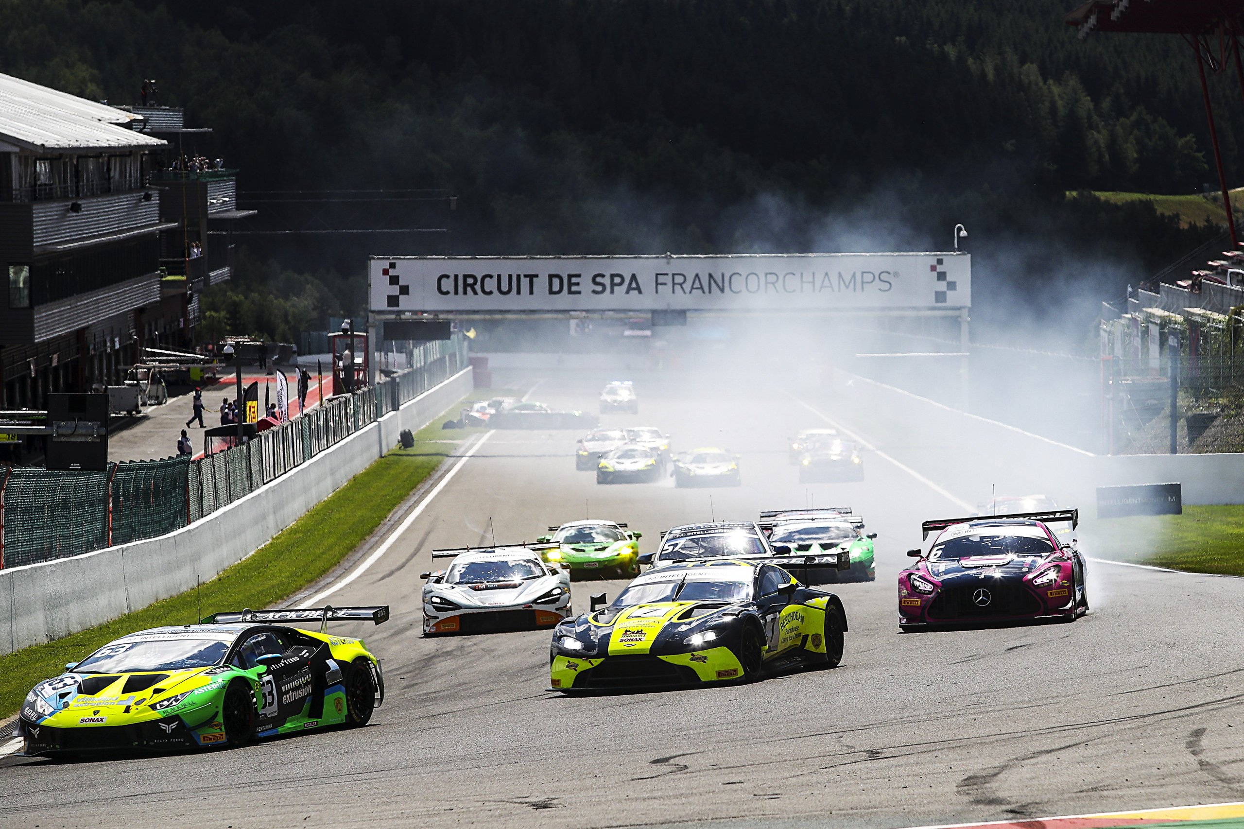 Huracán Gt3 Evo Locks Out The Top Two At Spa, And The 48-Second Margin Tells The Real Story 7 A pack of gt race cars including a green lamborghini huracán gt3 evo navigating a smoky turn under the spa-francorchamps circuit sign
