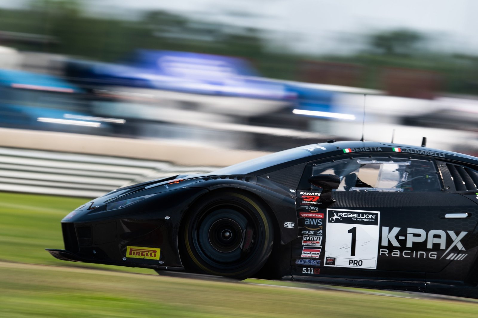The #1 K-PAX Racing Lamborghini Huracán GT3 EVO at speed on the NOLA Motorsports Park circuit, motion blur emphasizing its velocity