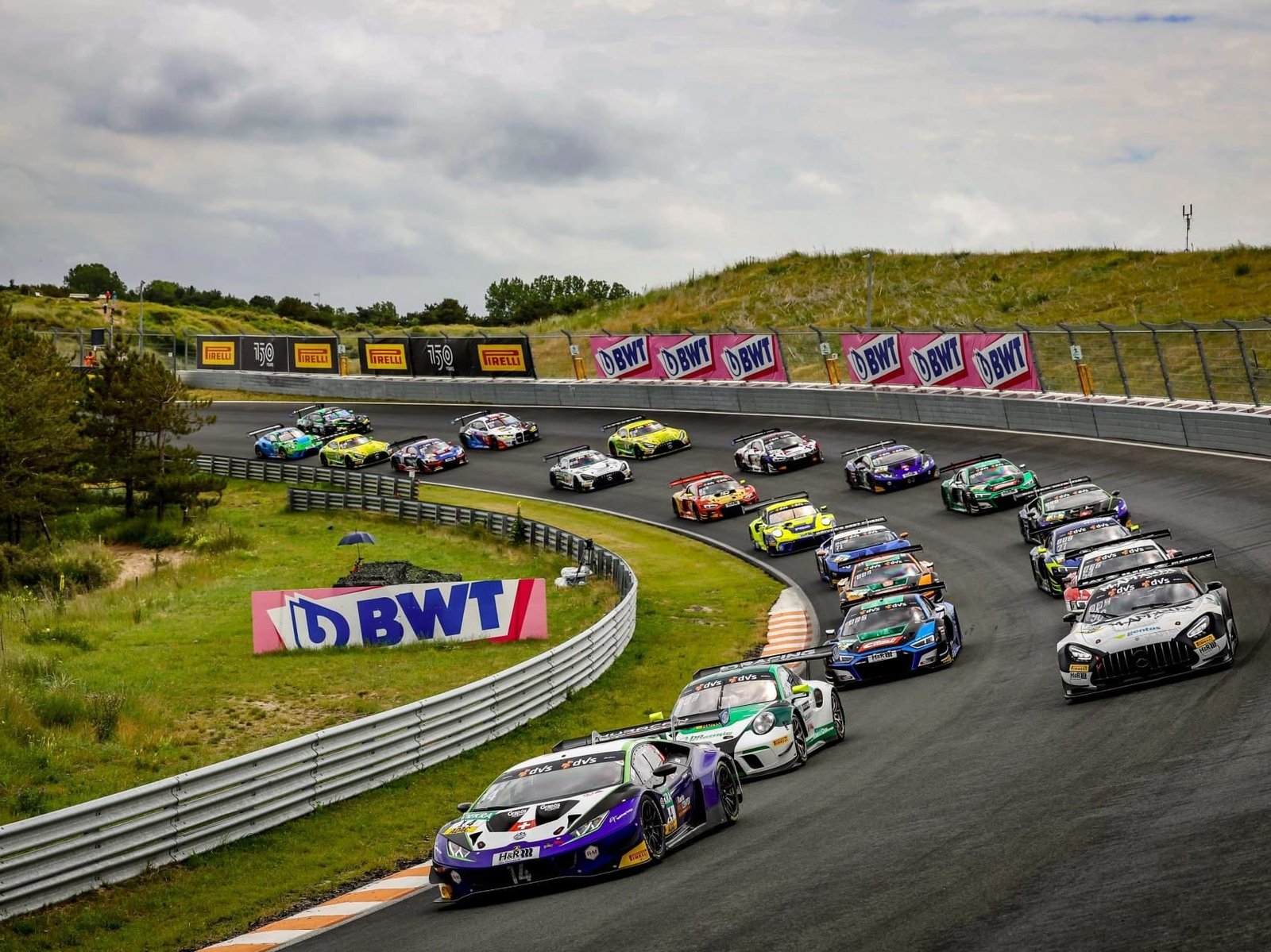 Multiple GT3 race cars including Lamborghini Huracán GT3 EVOs navigating a corner at the Zandvoort circuit during the ADAC GT Masters round