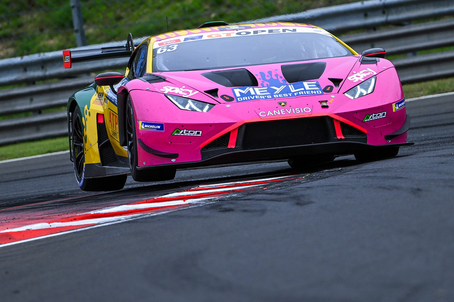 Two-Tenths Of A Second: How The Huracán Gt3 Evo2 Keeps Winning Before The Temerario Takes Over 3 Pink and yellow lamborghini huracán gt3 evo2 race car with sponsor decals cornering at speed on a racetrack