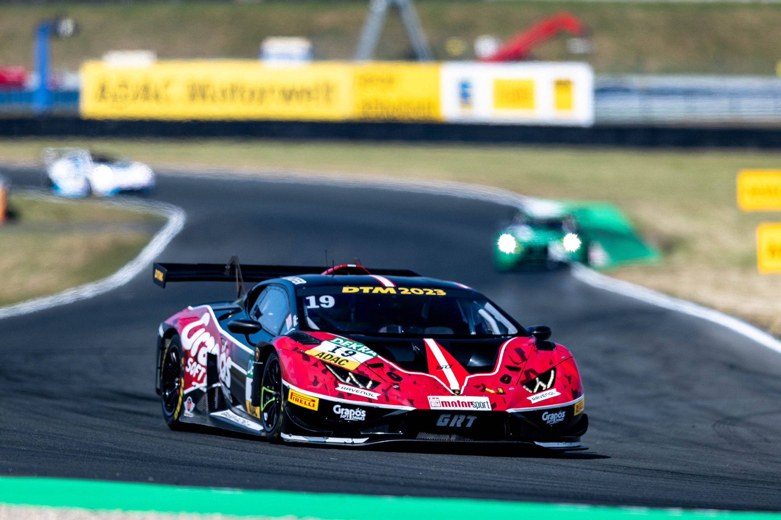Lamborghini huracán gt3 evo2 number 19 navigating a turn with competitors visible behind