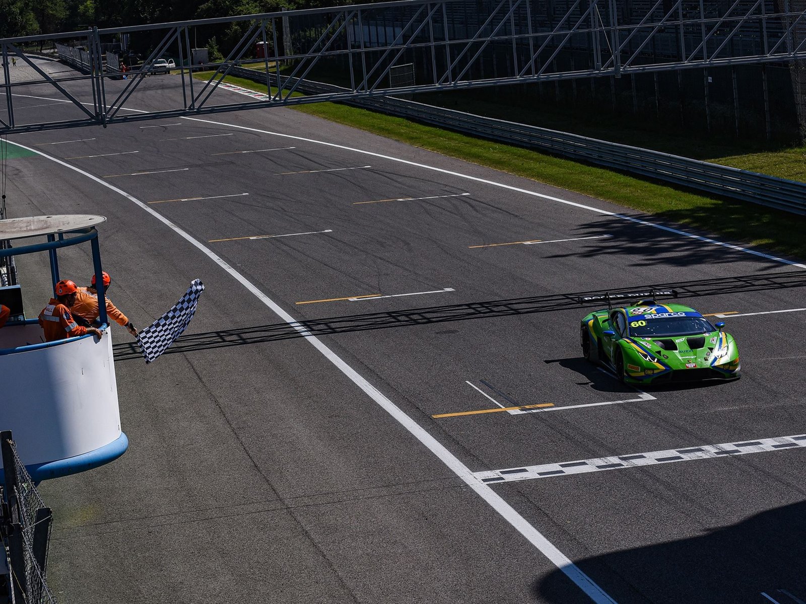 Green Lamborghini Huracán GT3 EVO2 crosses the finish line at Monza under the checkered flag