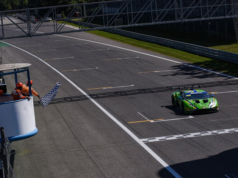 Green Lamborghini Huracán GT3 EVO2 crosses the finish line at Monza under the checkered flag