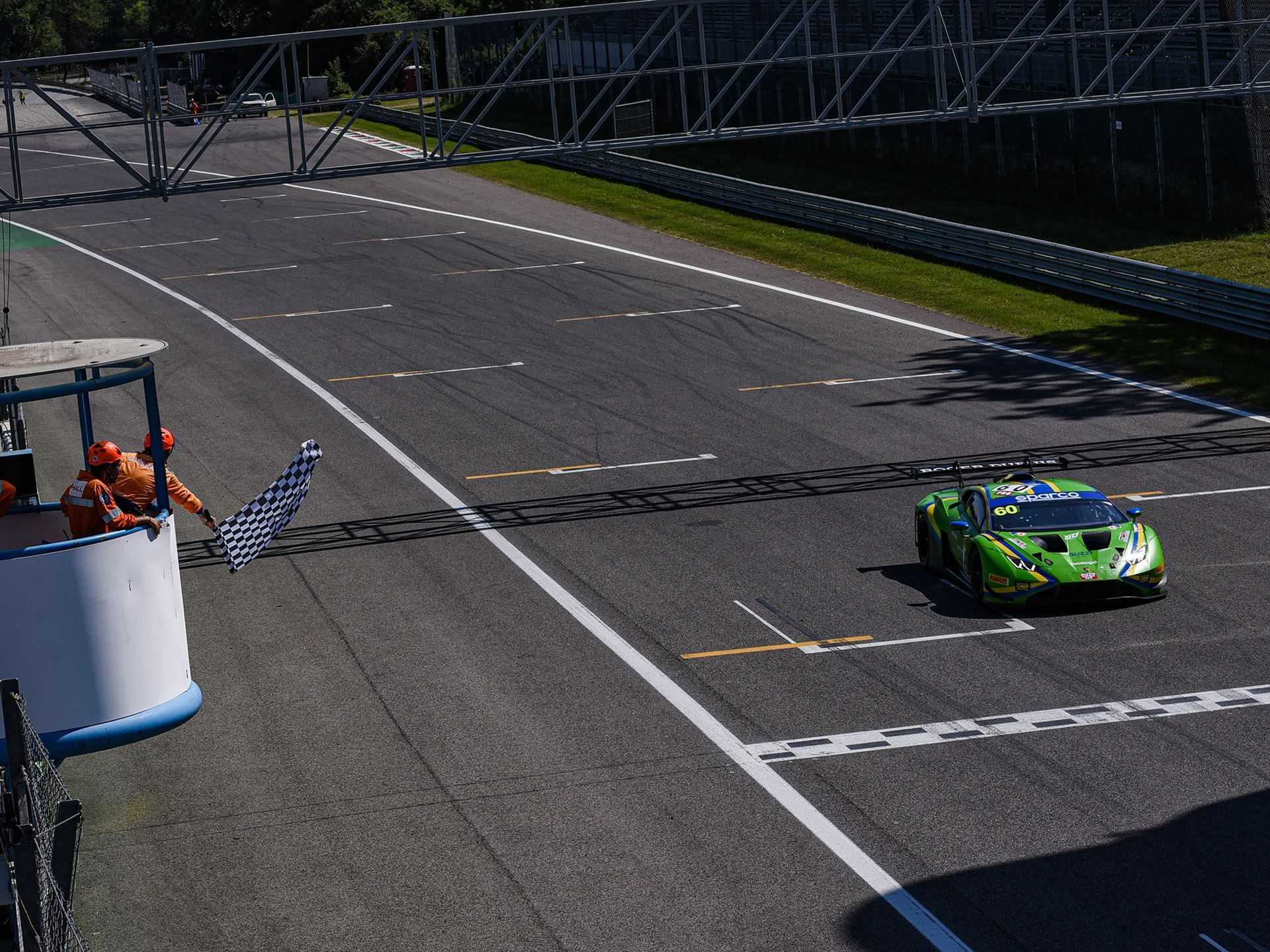 Green lamborghini huracán gt3 evo2 crosses the finish line at monza under the checkered flag