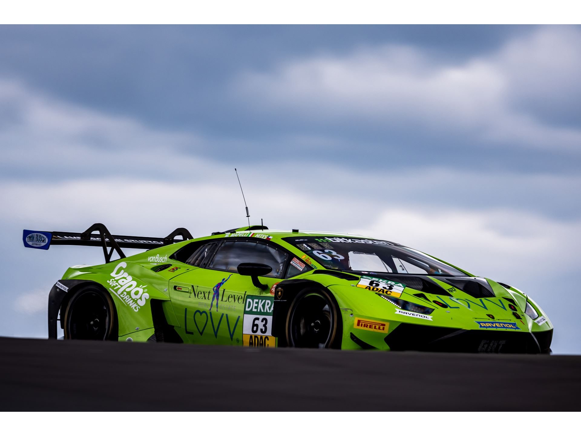 Huracán Gt3 Evo2 Scores Double Weekend Wins As Lamborghini Hits 50Th Adac Gt Masters Pole 5 Green lamborghini huracán gt3 evo2 number 63 racing on track under cloudy skies with large rear wing visible