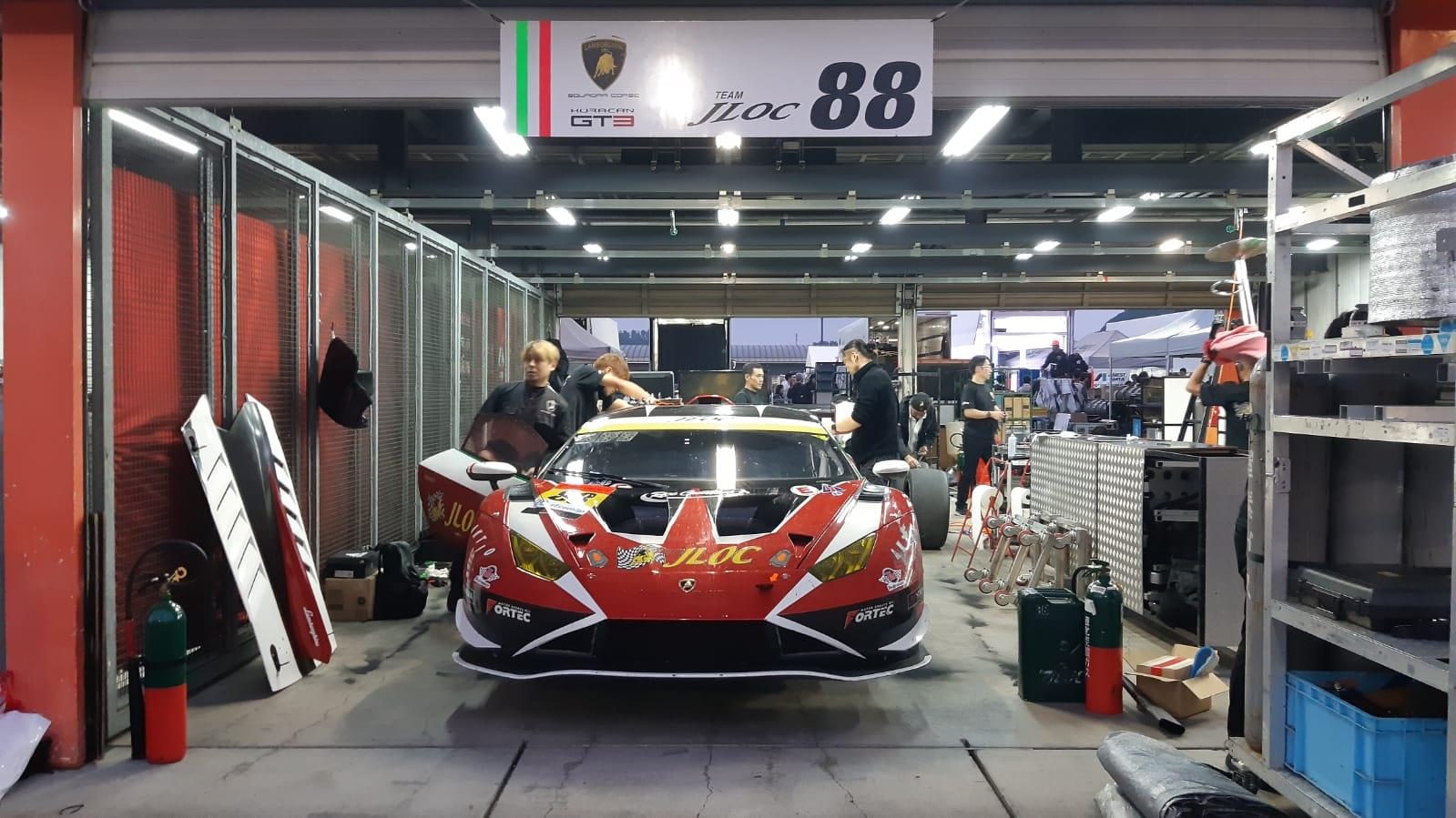 Jloc lamborghini huracán gt3 evo2 in the pit garage at motegi surrounded by team members and equipment