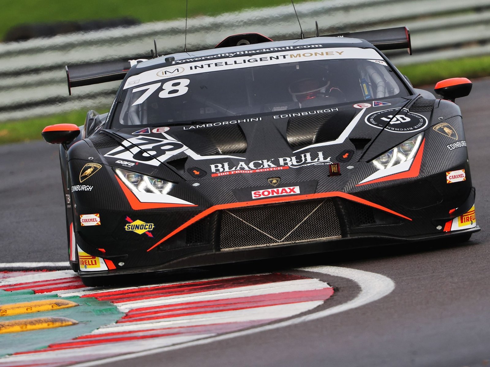 Barwell Motorsport's #78 Lamborghini Huracán GT3 EVO2 in black and orange livery navigating a wet corner at Donington Park during the British GT Championship