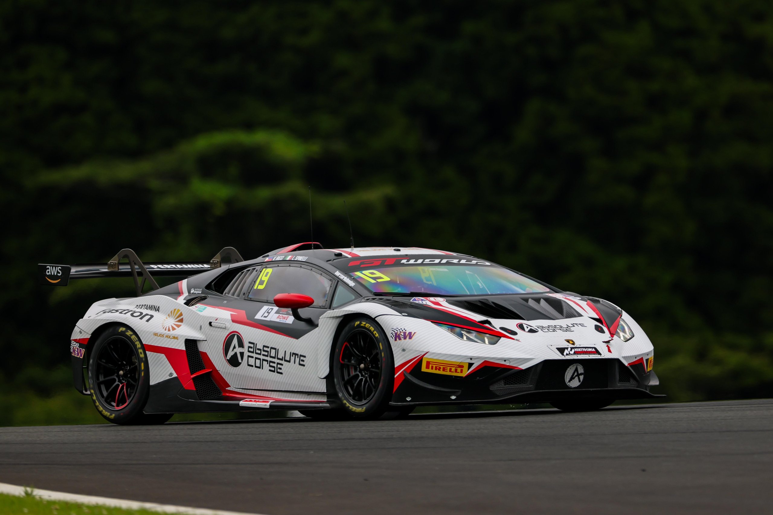 Lamborghini Huracán GT3 EVO race car in white, red, and black livery parked on a race track with a forested background
