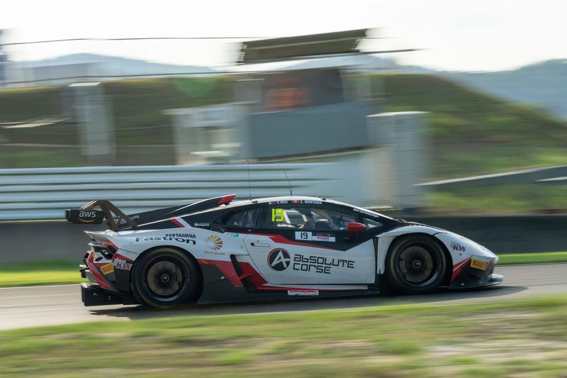 Lamborghini Huracán GT3 EVO race car in white, red, and black livery at speed on a race track with motion blur