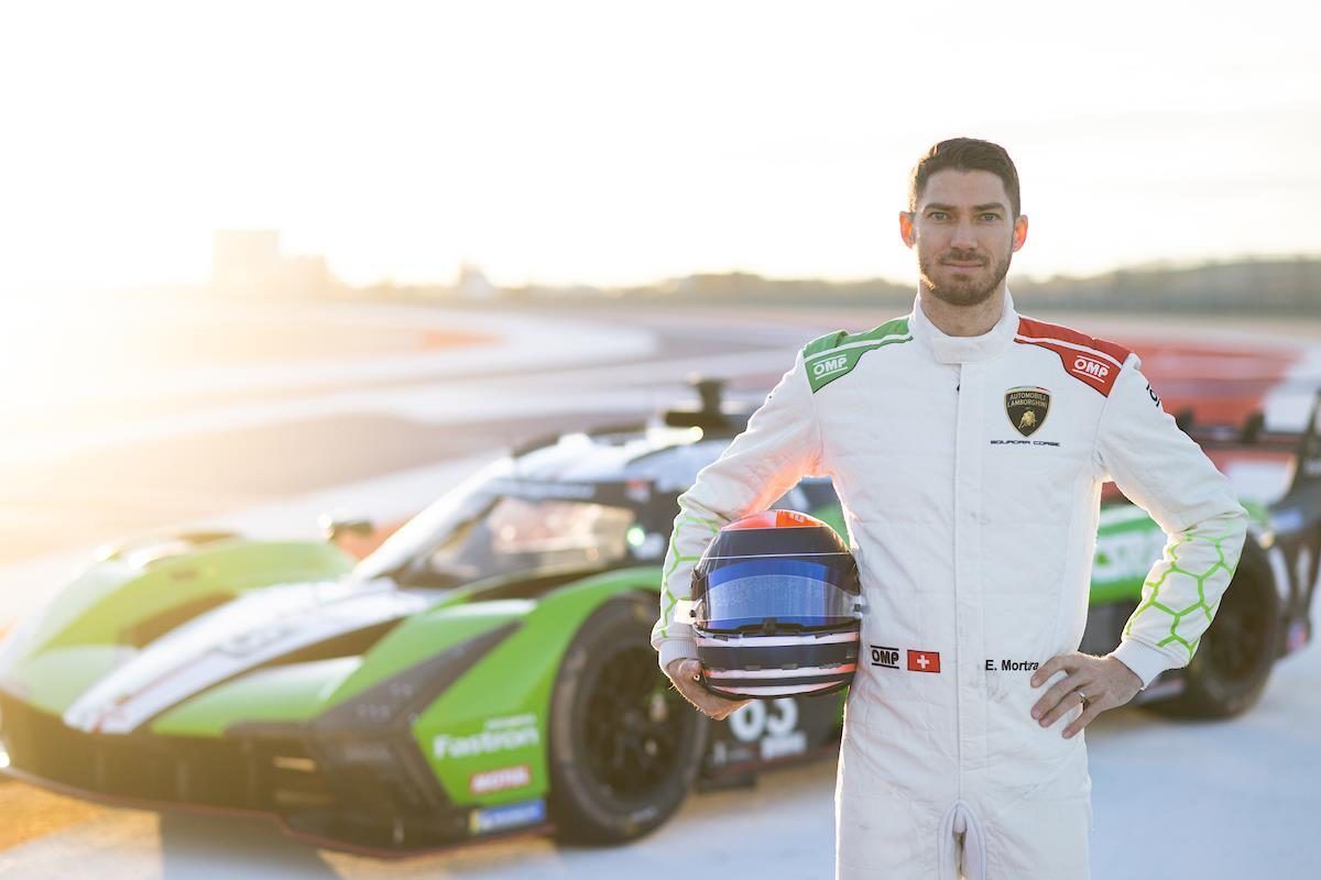 Lamborghini Sends The Huracán Gt3 To Macau For One Last Shot At A Victory It Has Never Claimed 3 Lamborghini factory driver in white racing suit holding helmet, standing in front of a lamborghini sc63 lmdh car at sunset on a race track