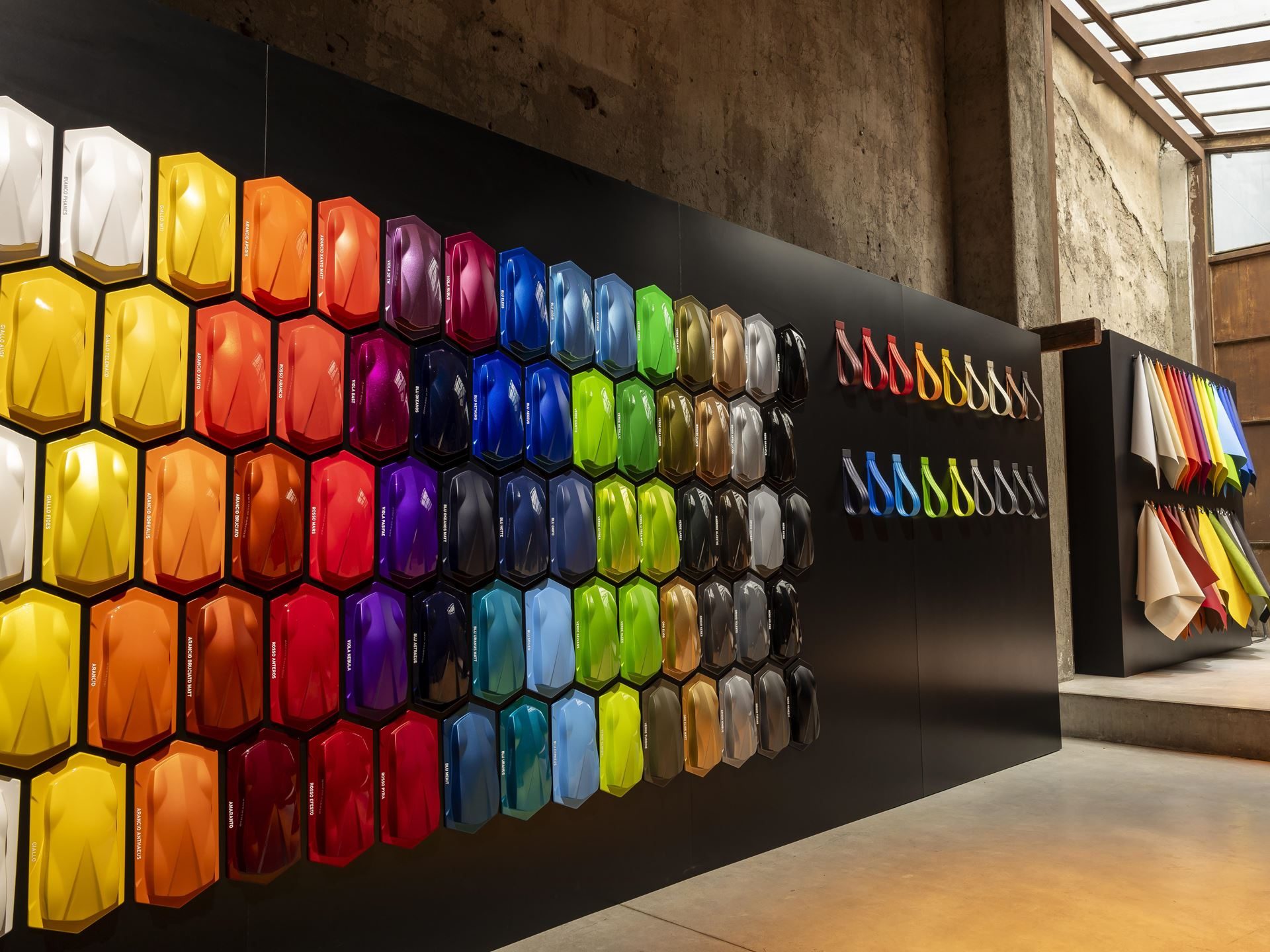 Twelve Camouflaged Sterrattos, A Michelin-Starred Dinner, And Tod'S Loafers: Inside Lamborghini'S Milan Design Week Power Play 7 Wall display of hexagonal paint samples in vibrant colors alongside interior material swatches at the ad personam studio