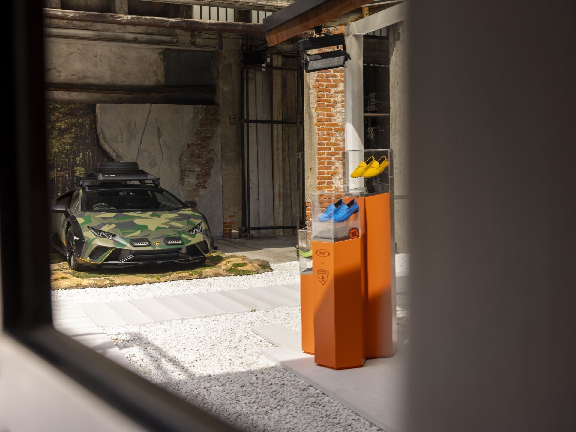 Twelve Camouflaged Sterrattos, A Michelin-Starred Dinner, And Tod'S Loafers: Inside Lamborghini'S Milan Design Week Power Play 5 Green camouflage huracán sterrato displayed with tod's shoe collection in the foreground at the milan design week event