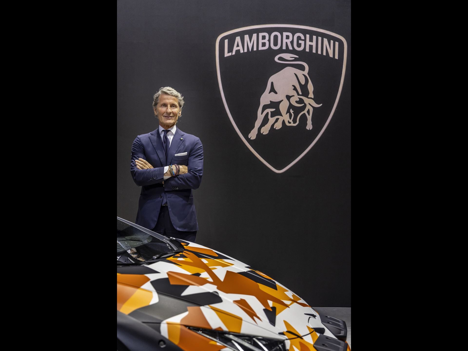 Twelve Camouflaged Sterrattos, A Michelin-Starred Dinner, And Tod'S Loafers: Inside Lamborghini'S Milan Design Week Power Play 11 Stephan winkelmann, ceo of lamborghini, standing next to an orange camouflage huracán sterrato against the lamborghini logo