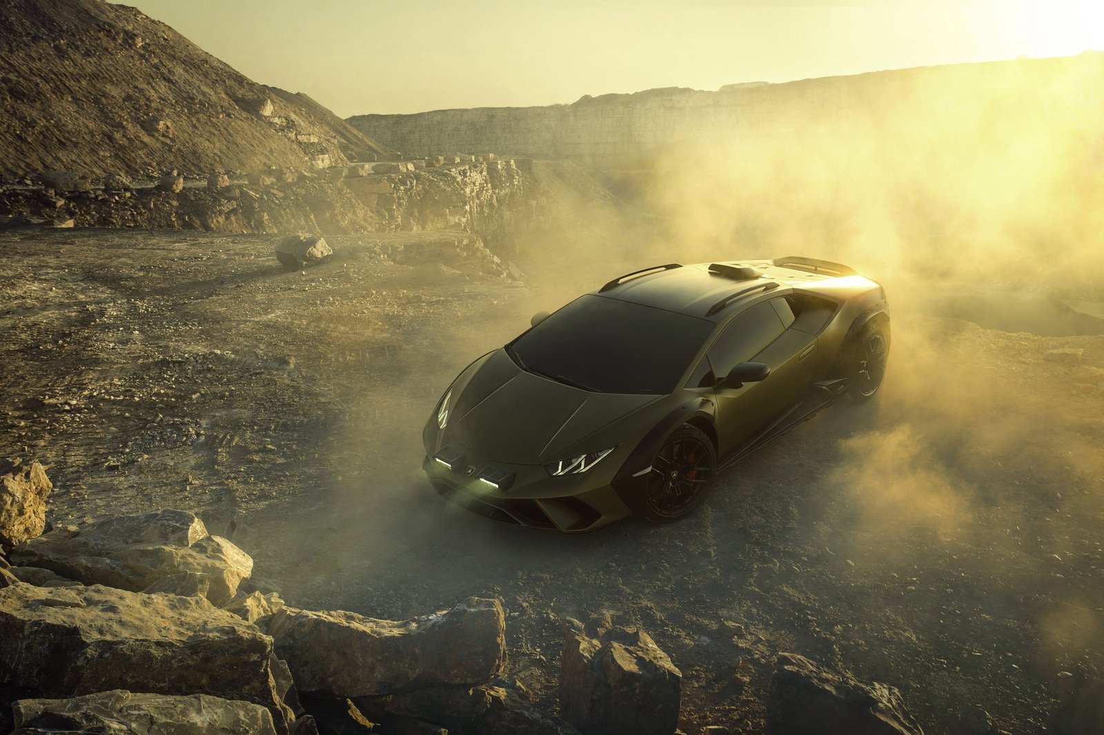 Lamborghini Huracán Sterrato in Verde Gea on rocky terrain with rally lights, roof scoop, and fender flares visible in golden haze