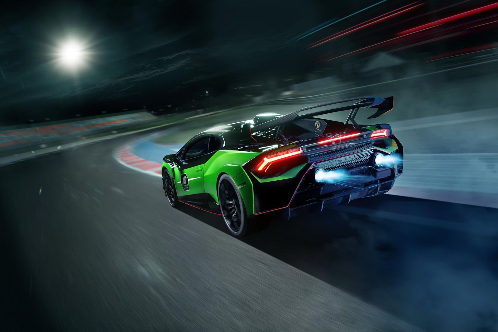 Lamborghini Huracán STO SC 10° Anniversario accelerating on track at night with visible exhaust flames and large rear wing
