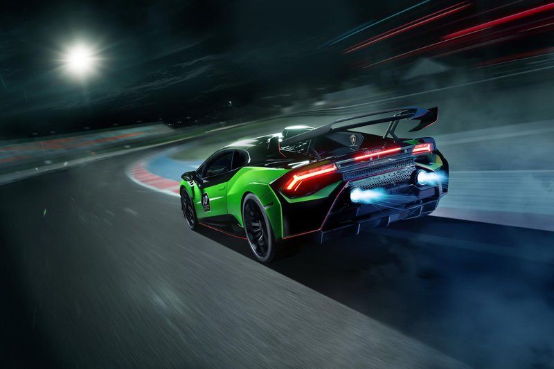Lamborghini Huracán STO SC 10° Anniversario accelerating on track at night with visible exhaust flames and large rear wing