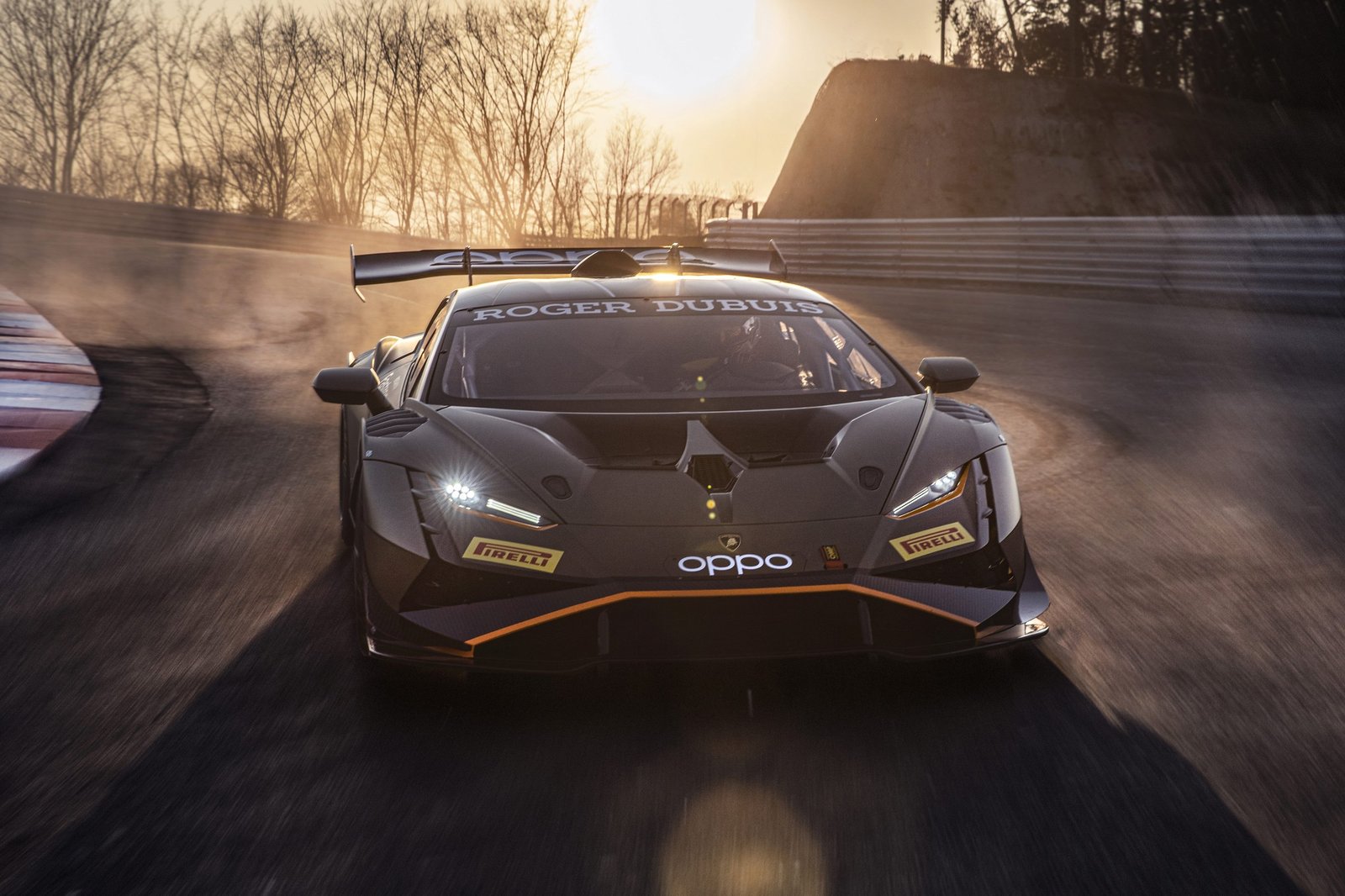 Lamborghini Huracán Super Trofeo EVO2 racing on track at sunset with dramatic sky and sun flare