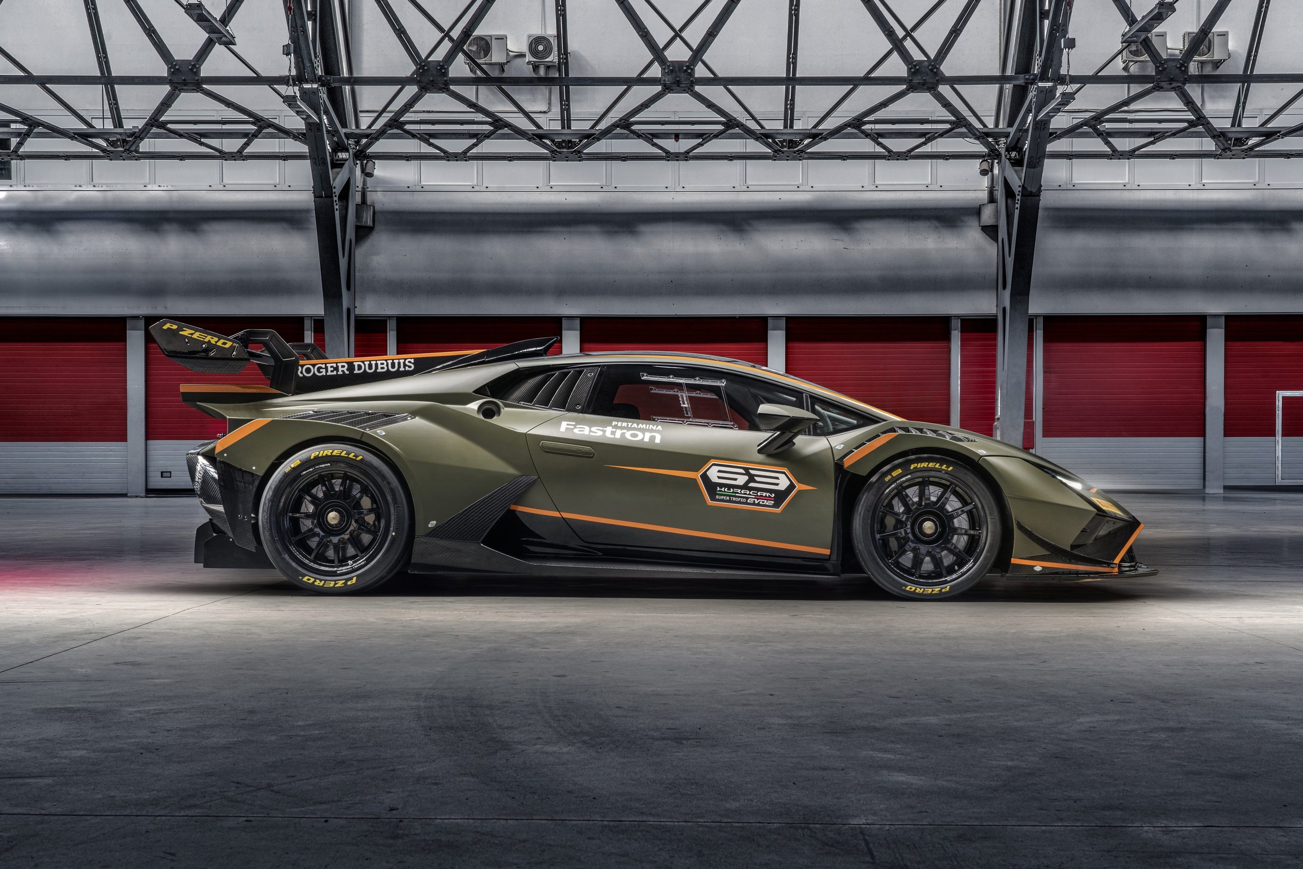 The Huracán Super Trofeo Evo2 Previews Lamborghini'S Next Design Language From The Track 7 Lamborghini huracán super trofeo evo2 in matte green with orange racing livery displayed in an industrial hangar, side view