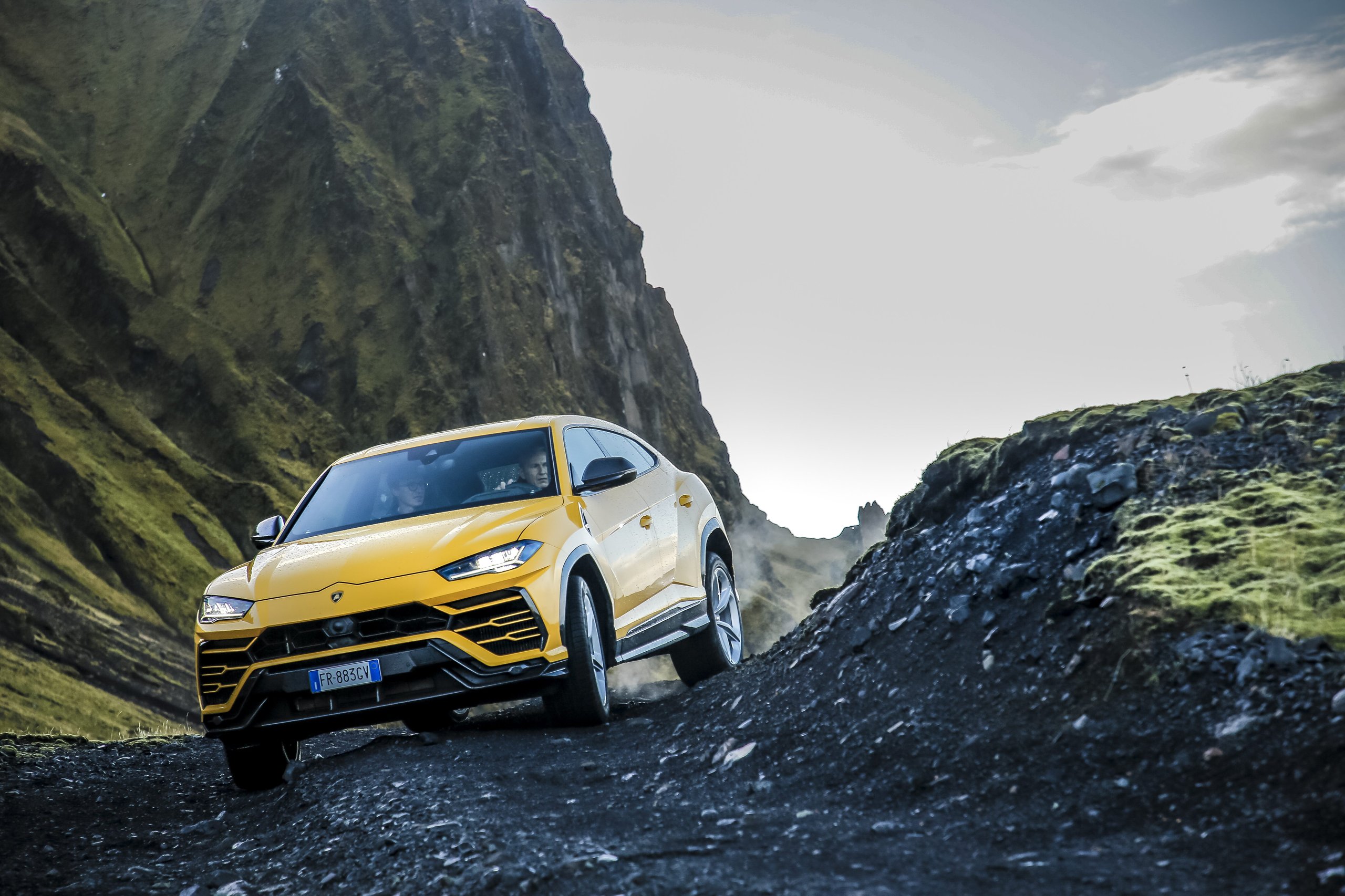 Lamborghini'S €1.8 Billion Gamble: Record 2021 Profits Fund The End Of Pure Combustion 5 Yellow lamborghini urus driving on a rocky off-road path with mountains in the background