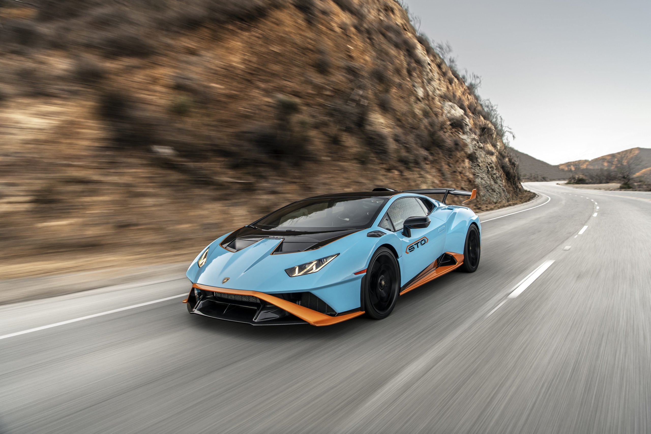 How 8,405 Cars And One Suv Are Funding Lamborghini'S €1.5 Billion Bet On Electrification 11 Blue lamborghini huracán sto with orange accents speeding along a winding mountain road with motion blur