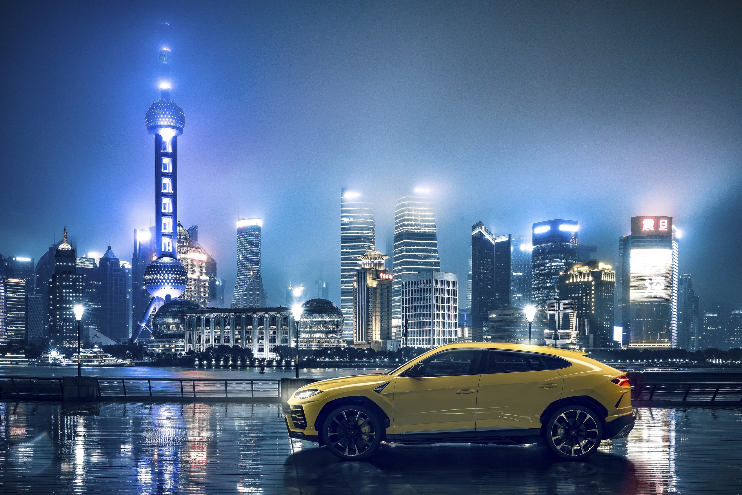 How 8,405 Cars And One Suv Are Funding Lamborghini'S €1.5 Billion Bet On Electrification 3 Yellow lamborghini urus parked overlooking an illuminated cityscape at night
