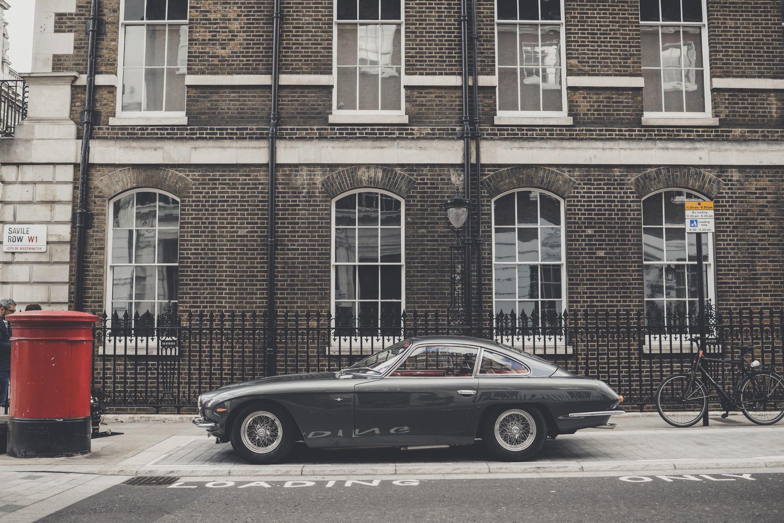 Classic dark grey lamborghini 400 gt 2+2 parked on a london street beside a red post box