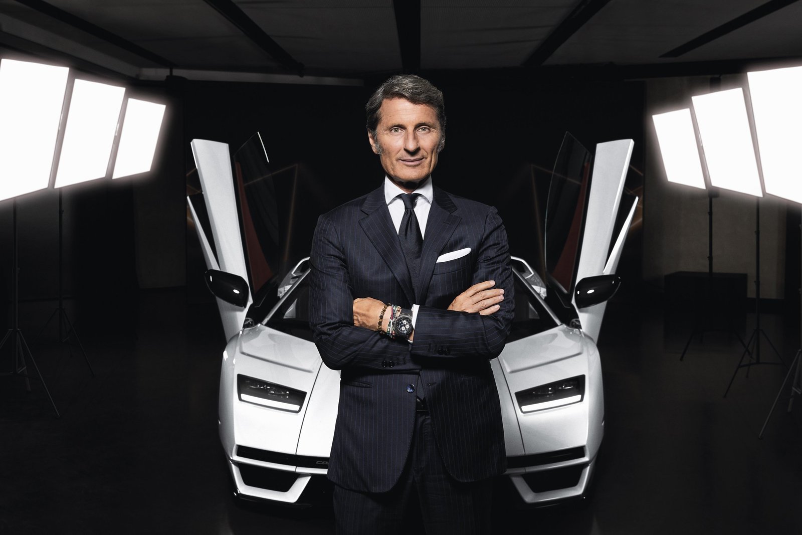 Stephan Winkelmann, CEO of Automobili Lamborghini, standing before a white Countach LPI 800-4 with scissor doors open in a studio setting