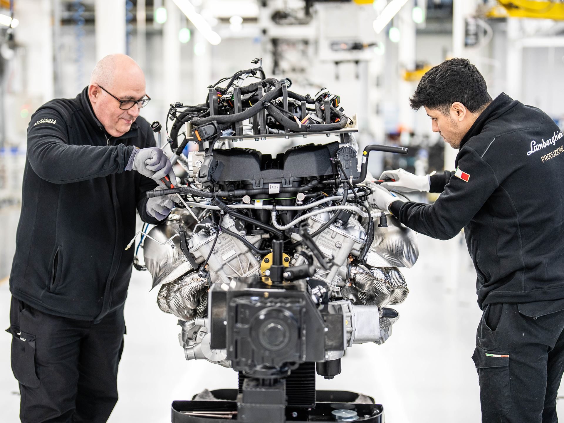 Two technicians hand-assembling a lamborghini v12 engine in the sant'agata bolognese factory