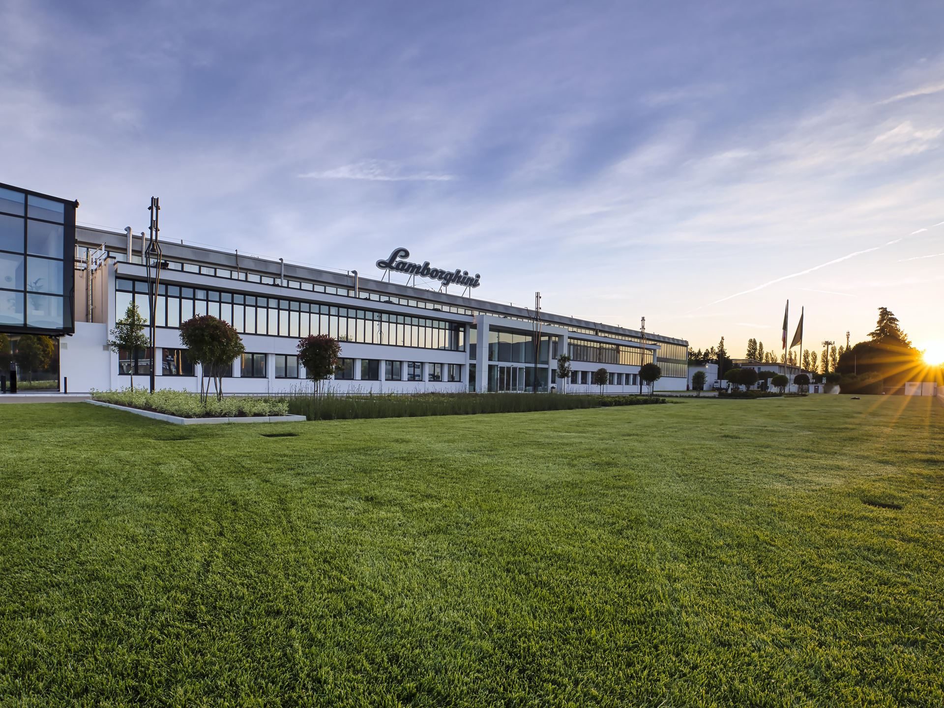 Modern exterior of the lamborghini factory building in sant'agata bolognese at sunset with a green lawn in the foreground